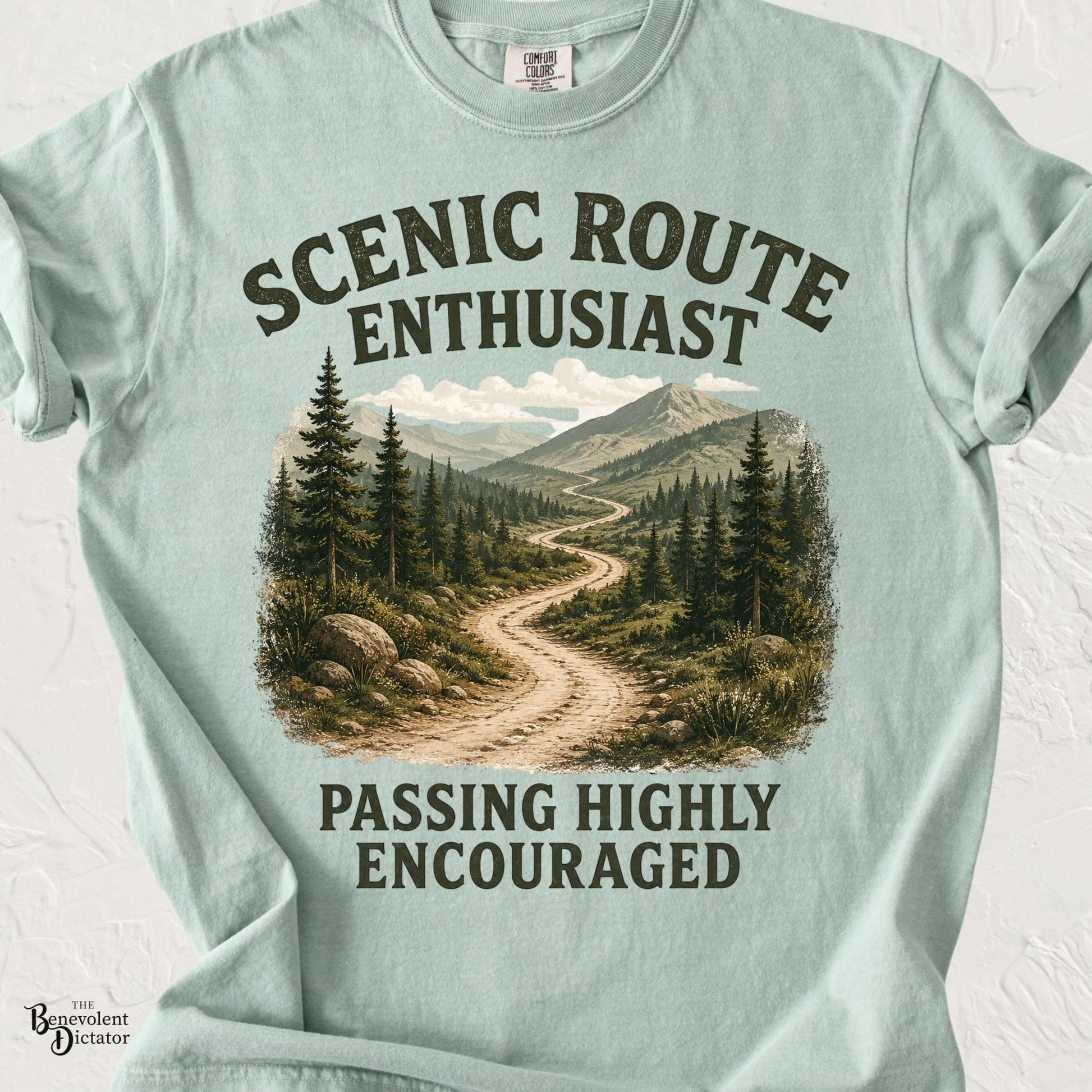 Vintage mountain landscape featuring a winding scenic trail with the phrase "Scenic Route Enthusiast – Passing Highly Encouraged" in distressed retro typography.