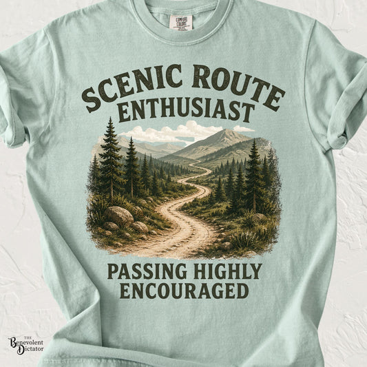Vintage mountain landscape featuring a winding scenic trail with the phrase "Scenic Route Enthusiast – Passing Highly Encouraged" in distressed retro typography.