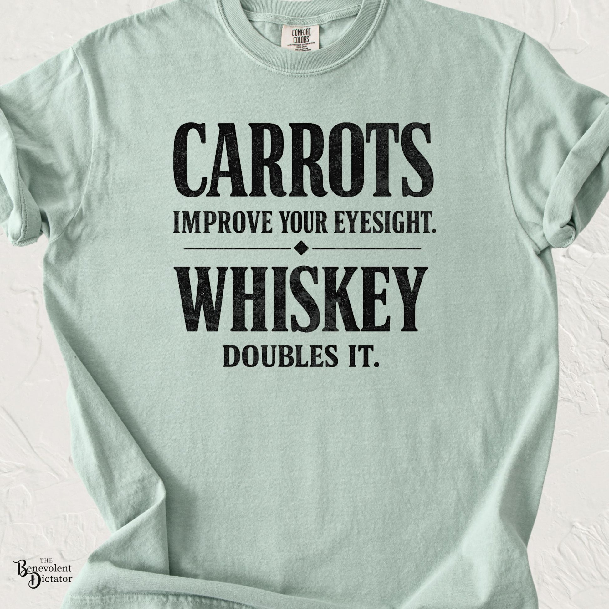 Bay green typography t-shirt featuring the funny quote “Carrots Improve Your Eyesight. Whiskey Doubles It.” in distressed black lettering.