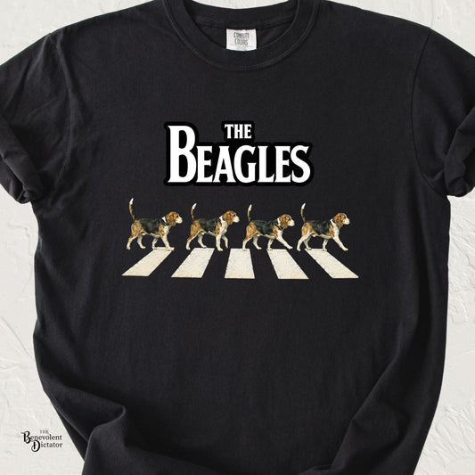 Funny Beagles t-shirt parody featuring four beagle dogs walking across a striped crosswalk beneath bold retro text reading “The Beagles.”