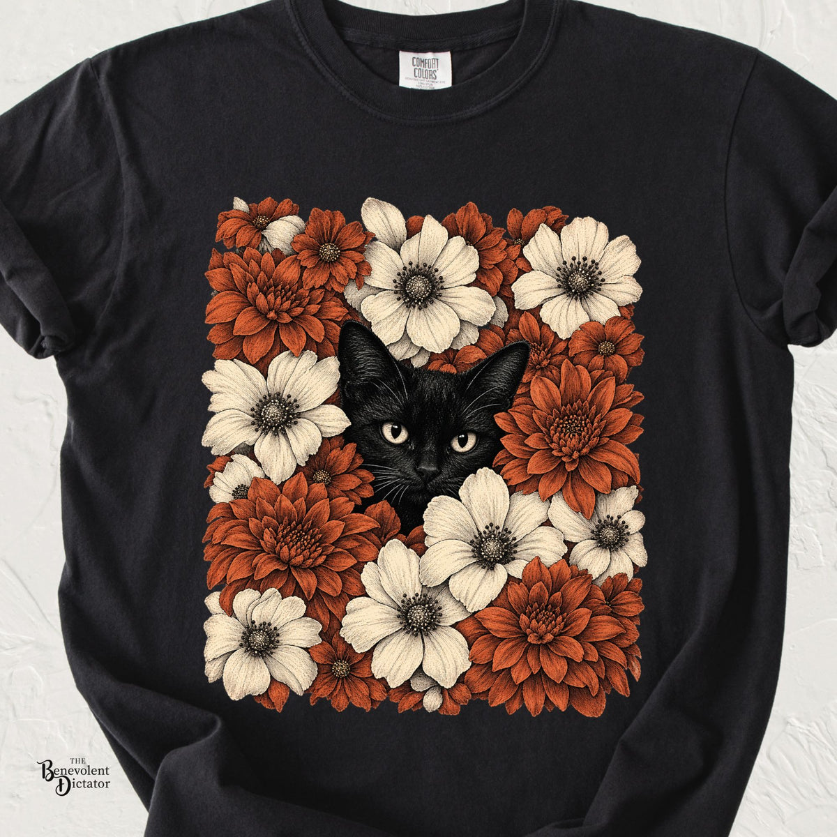 Black Comfort Colors t-shirt featuring a black cat peeking through a dense arrangement of rust orange and cream vintage botanical flowers.