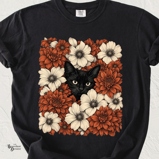 Black Comfort Colors t-shirt featuring a black cat peeking through a dense arrangement of rust orange and cream vintage botanical flowers.