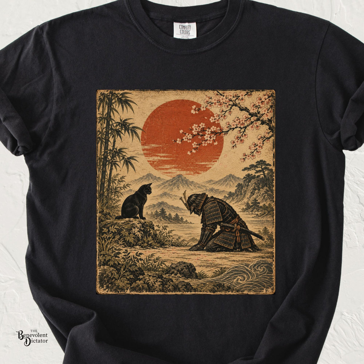 Black Comfort Colors t-shirt featuring a vintage Japanese-inspired scene of a kneeling samurai bowing before a black cat beneath cherry blossoms and a red sun.