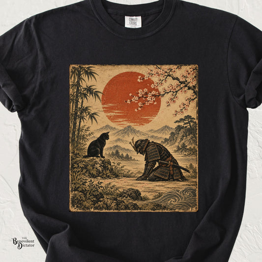 Black Comfort Colors t-shirt featuring a vintage Japanese-inspired scene of a kneeling samurai bowing before a black cat beneath cherry blossoms and a red sun.