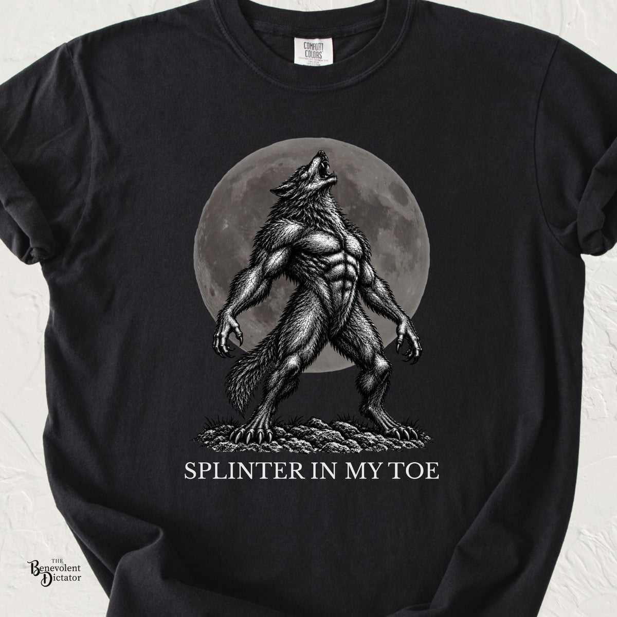Black Comfort Colors t-shirt featuring a muscular werewolf howling dramatically in front of a full moon with the words “Splinter in My Toe.”