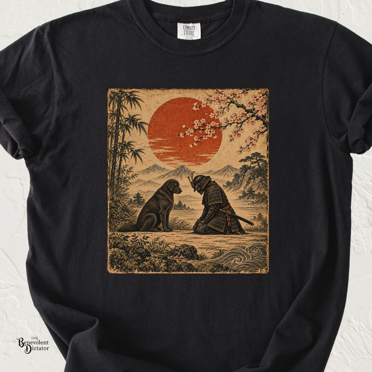 Black Comfort Colors t-shirt featuring a vintage Japanese-style illustration of a kneeling samurai bowing respectfully before a seated dog beneath a red sun, cherry blossoms and mountain landscape.