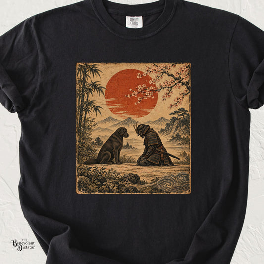 Black Comfort Colors t-shirt featuring a vintage Japanese-style illustration of a kneeling samurai bowing respectfully before a seated dog beneath a red sun, cherry blossoms and mountain landscape.