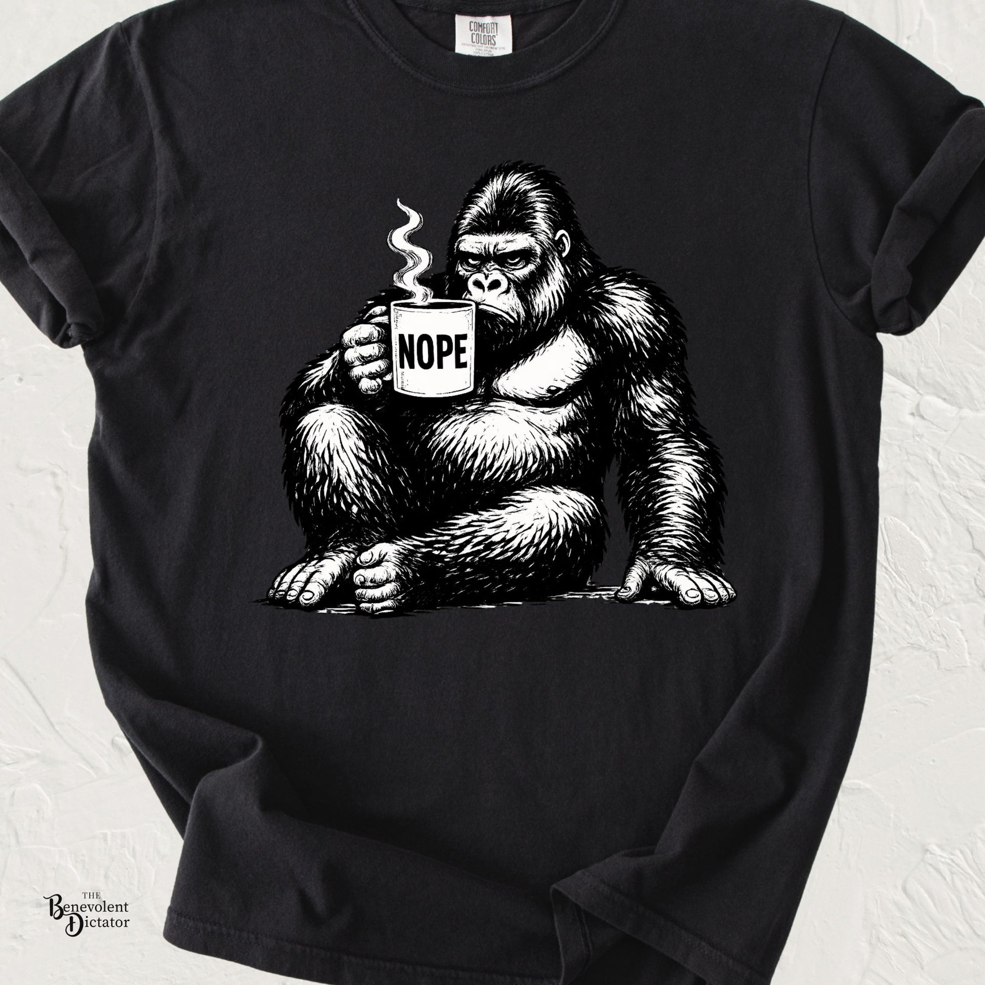 Black graphic t-shirt featuring a grumpy gorilla holding a coffee mug labeled “NOPE” with steam rising from the mug.