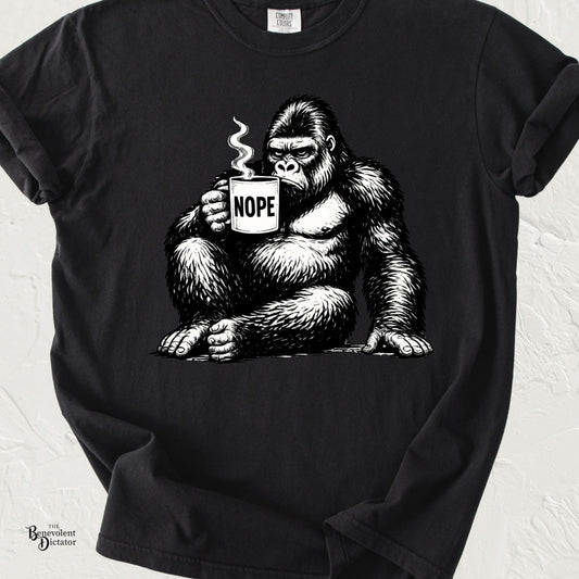 Black graphic t-shirt featuring a grumpy gorilla holding a coffee mug labeled “NOPE” with steam rising from the mug.
