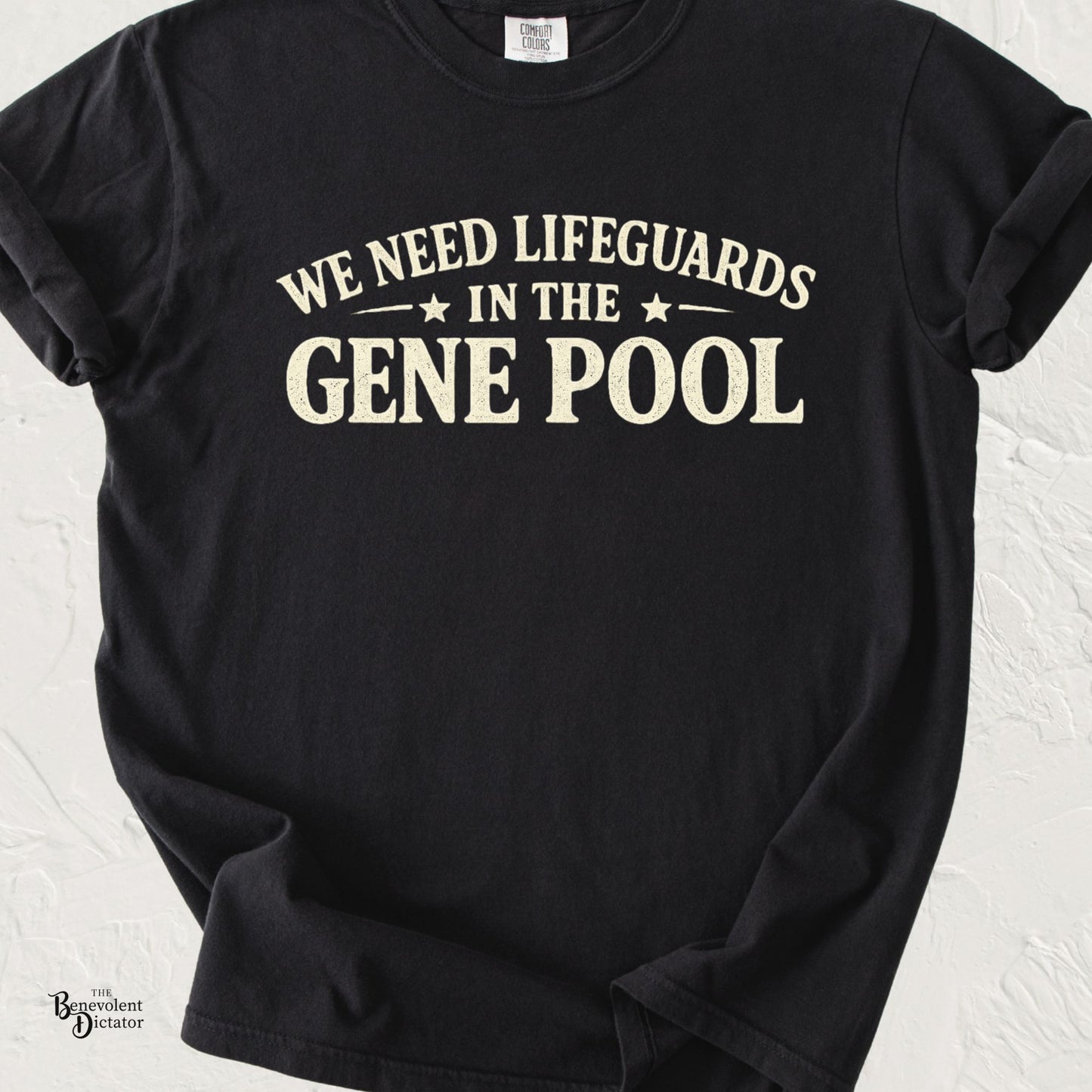 Black Comfort Colors t-shirt featuring distressed cream typography that reads “We Need Lifeguards in the Gene Pool.”