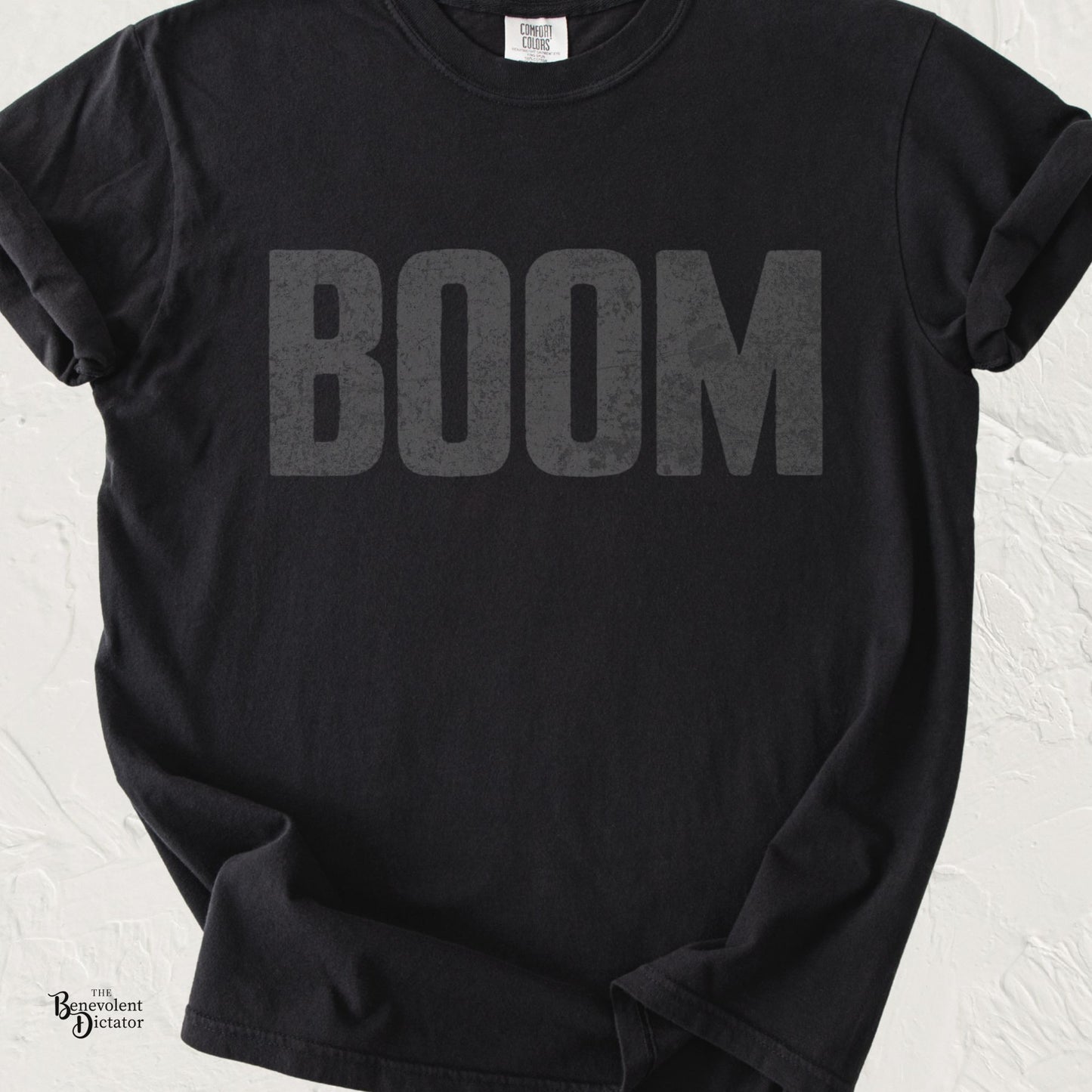 Black Comfort Colors t-shirt featuring the word "BOOM" in oversized distressed charcoal gray typography across the chest.