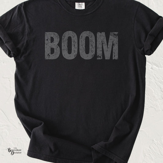 Black Comfort Colors t-shirt featuring the word "BOOM" in oversized distressed charcoal gray typography across the chest.