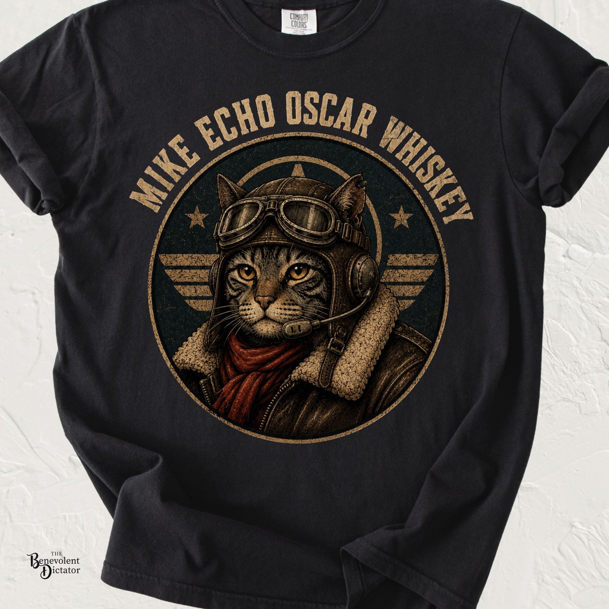 Black Comfort Colors t-shirt featuring a vintage aviator cat wearing a leather flight helmet, goggles, and headset with the words "Mike Echo Oscar Whiskey" in distressed lettering.
