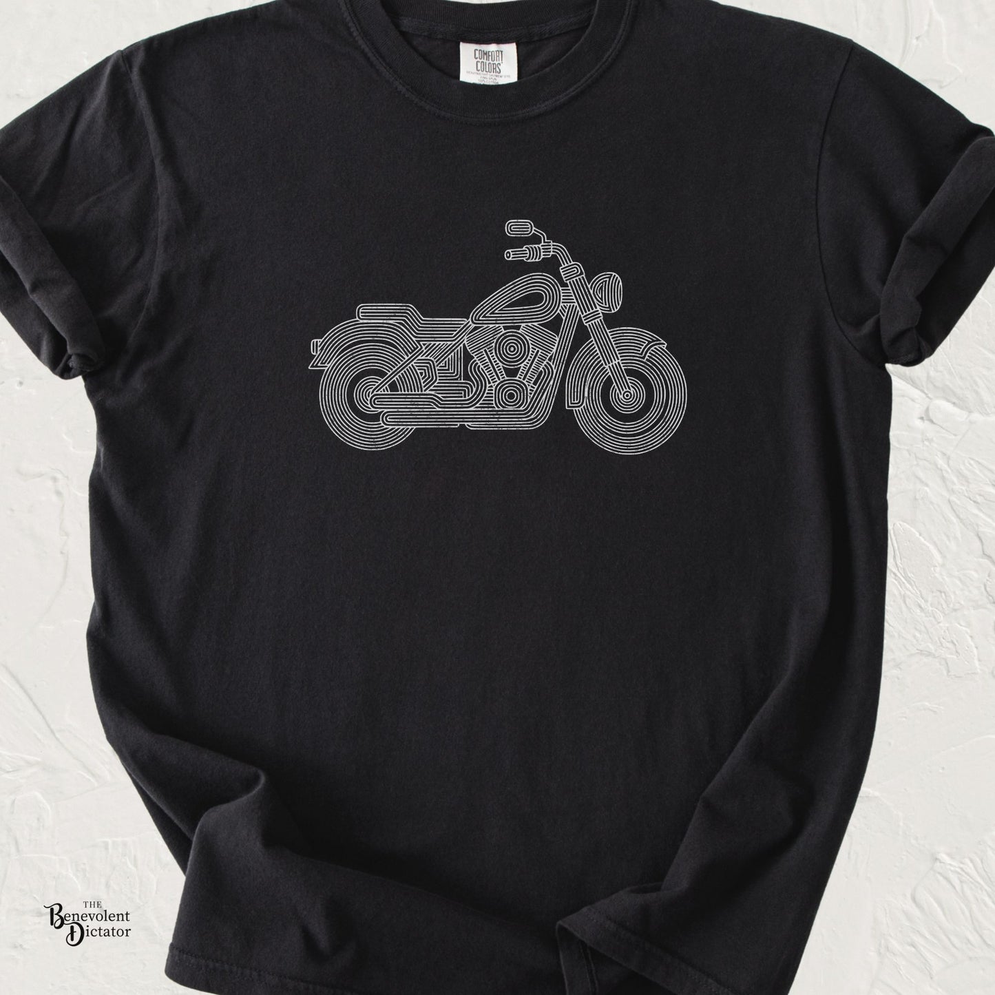 Black Comfort Colors t-shirt featuring a minimalist parallel-line illustration of a classic cruiser motorcycle in clean white line art.