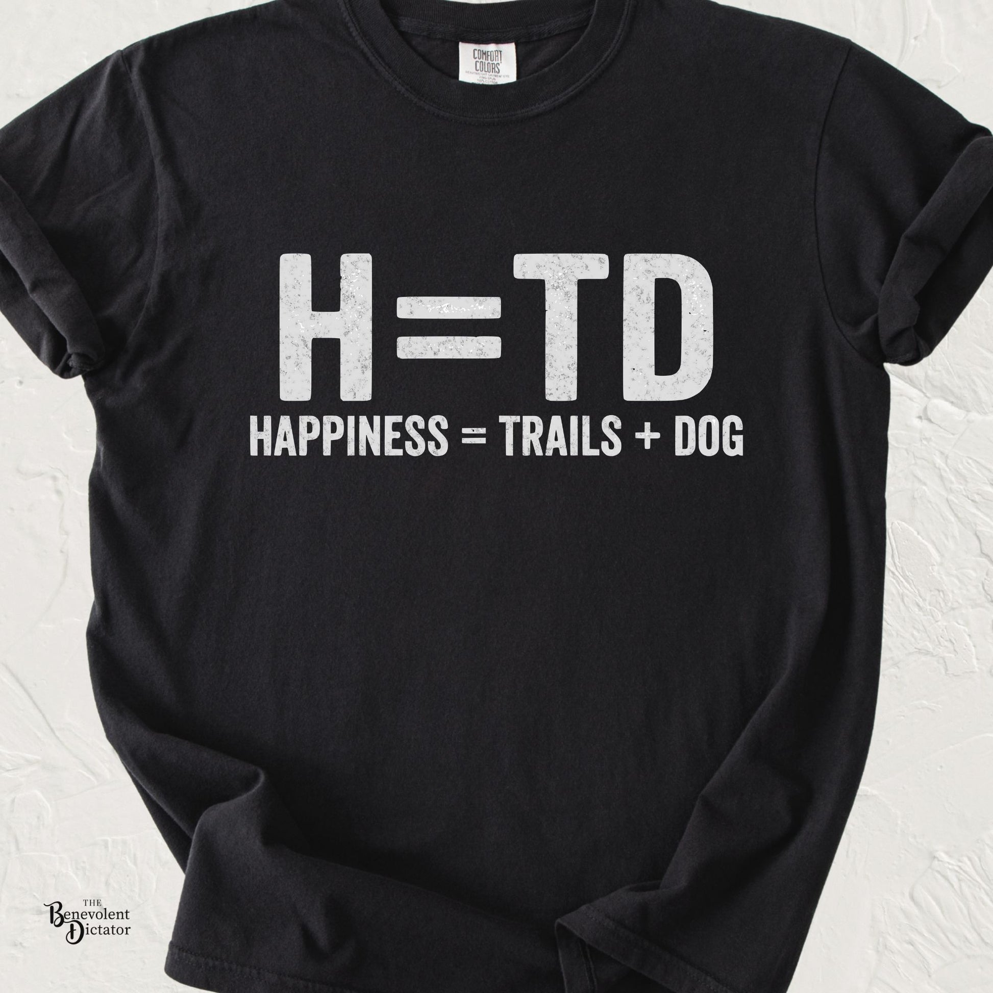 Funny typography T-shirt featuring the equation "H = TD" with the caption "Happiness = Trails + Dog" in distressed white lettering on a black Comfort Colors shirt.