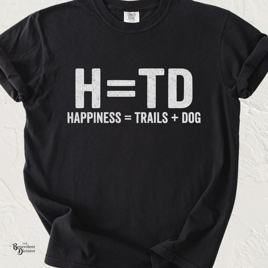 Funny typography T-shirt featuring the equation "H = TD" with the caption "Happiness = Trails + Dog" in distressed white lettering on a black Comfort Colors shirt.