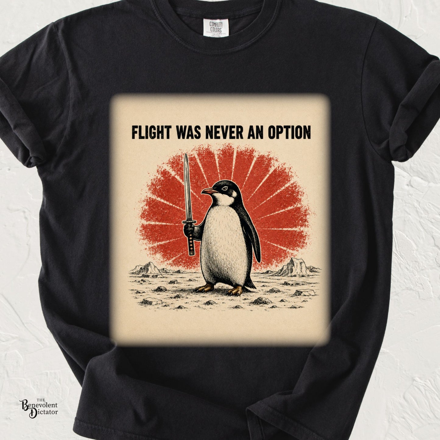 Vintage-style illustration of a determined penguin holding a sword beneath the phrase "Flight Was Never an Option" with a distressed red rising sun background on a Comfort Colors® t-shirt.