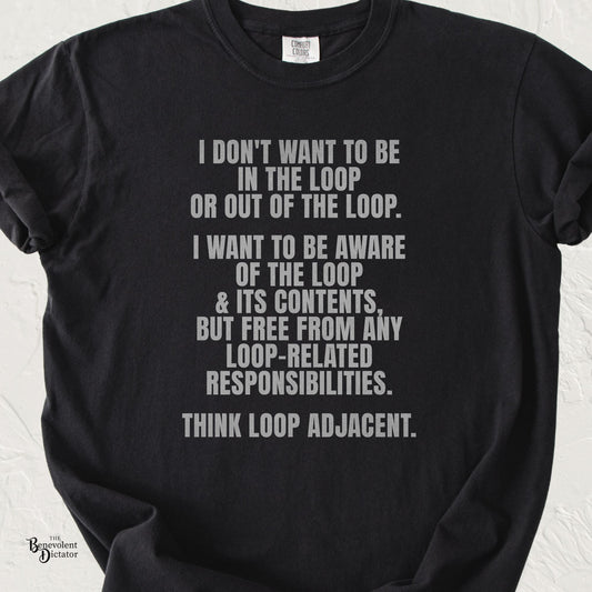 Funny text graphic t-shirt reading “I don’t want to be in the loop or out of the loop” and ending with “Think loop adjacent” in bold minimalist typography.