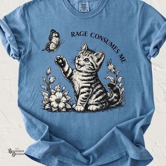 Blue Comfort Colors t-shirt featuring an innocent tabby kitten reaching toward a butterfly, surrounded by flowers, with the phrase "Rage Consumes Me" arched overhead in vintage lettering.