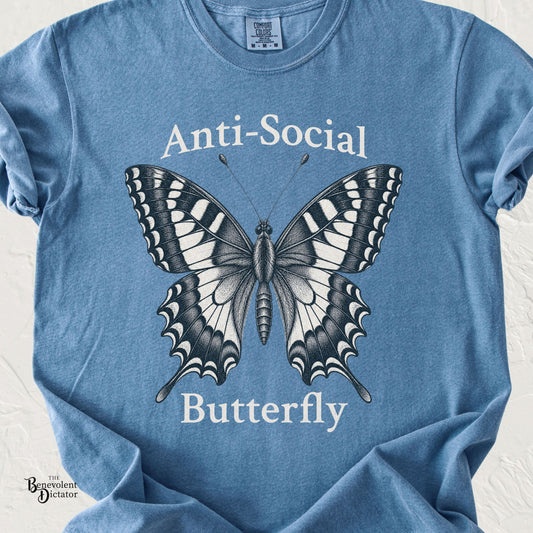 Blue Comfort Colors t-shirt featuring a detailed vintage butterfly illustration with the phrase “Anti-Social Butterfly” in classic serif typography.