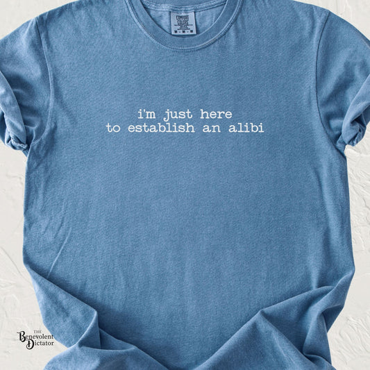 Blue Jean Comfort Colors t-shirt with minimalist typewriter text reading “I’m just here to establish an alibi” in light grey.