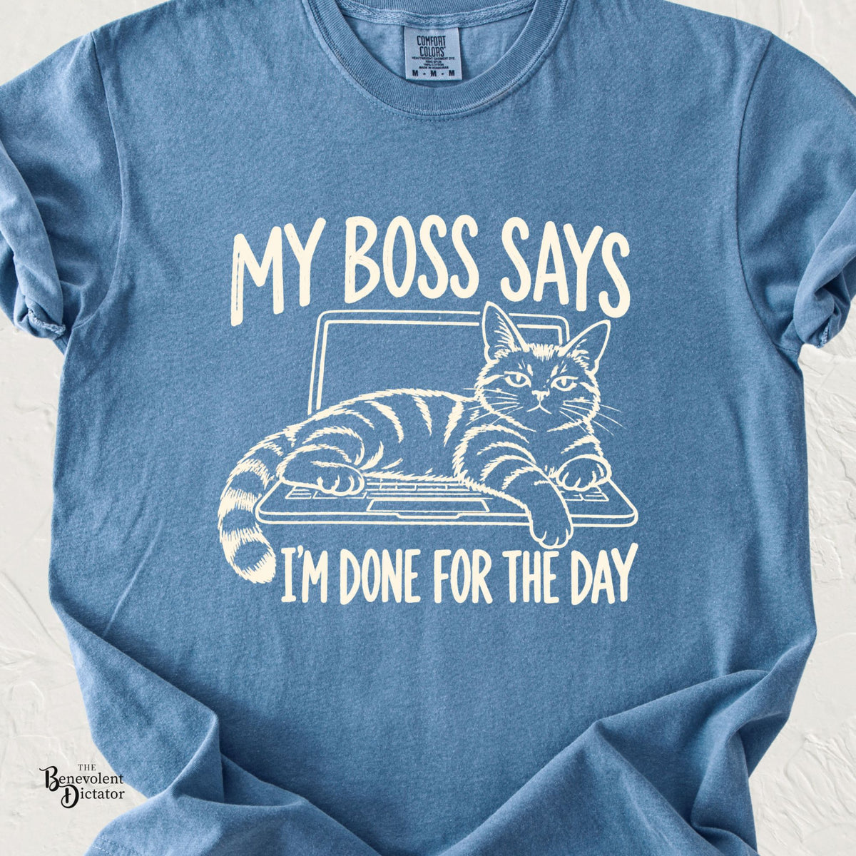 A heathered blue crewneck t-shirt featuring a white graphic of a tabby cat lounging on a laptop with the text 'MY BOSS SAYS I'M DONE FOR THE DAY'.