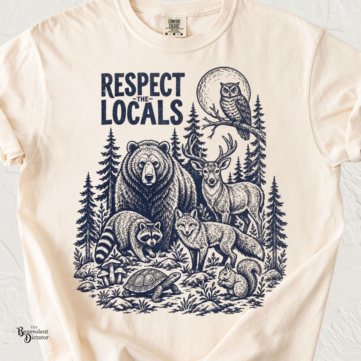 Respect the Locals wildlife t-shirt featuring a vintage navy illustration of a bear, deer, fox, raccoon, owl, turtle, squirrel, and forest landscape.