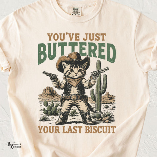 Funny cowboy cat Comfort Colors tee featuring “You’ve Just Buttered Your Last Biscuit.” A cute western shirt with plenty of frontier attitude.