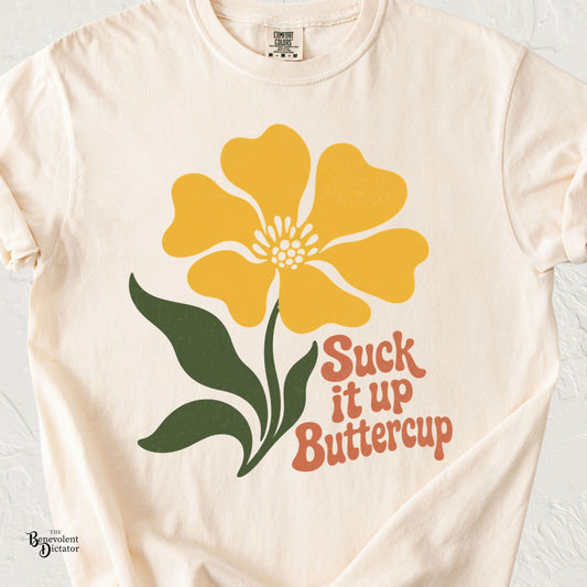 Ivory Comfort Colors t-shirt featuring a retro yellow flower with green leaves and orange “Suck It Up Buttercup” typography.