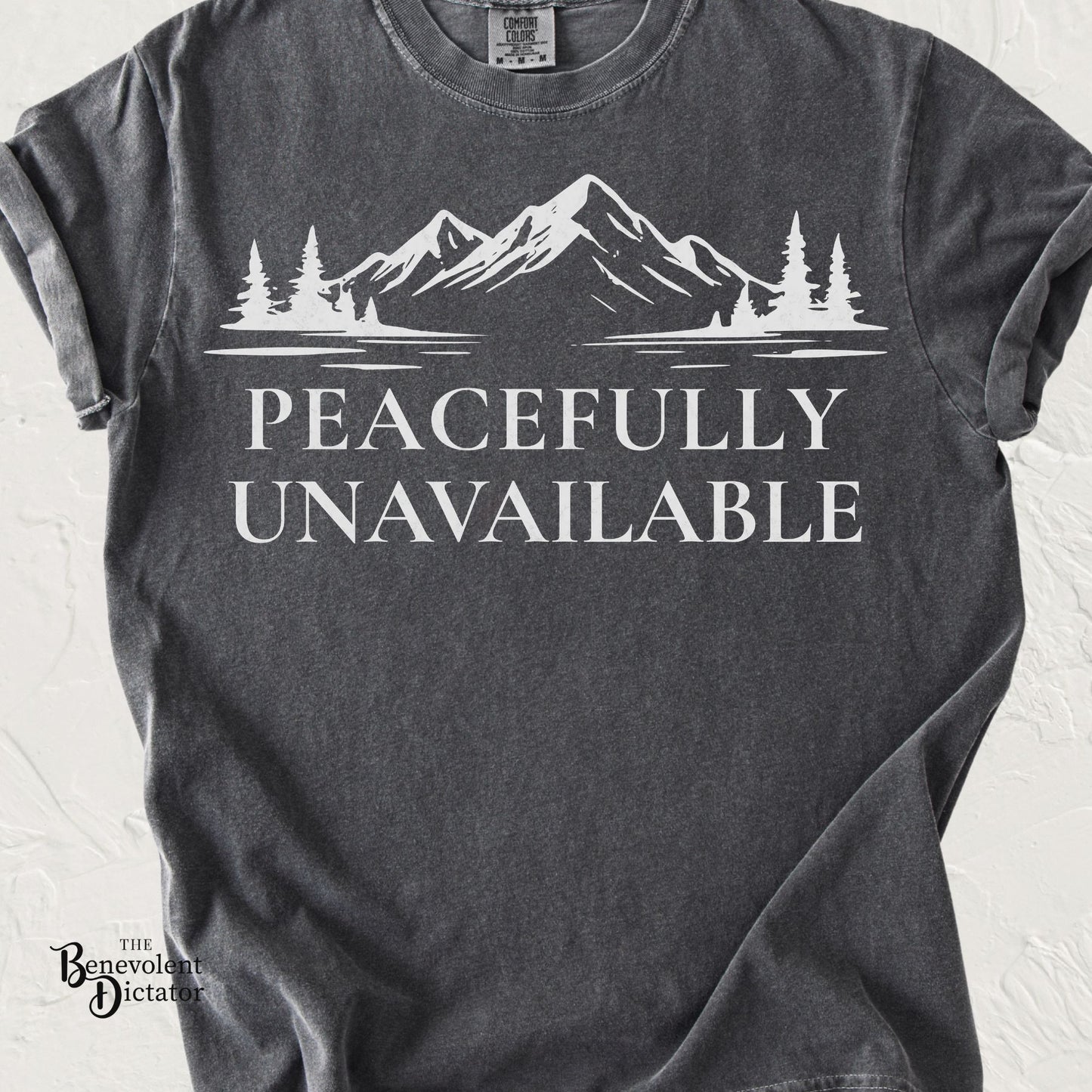 Mountain graphic t-shirt featuring the phrase Peacefully Unavailable with a minimalist wilderness design.