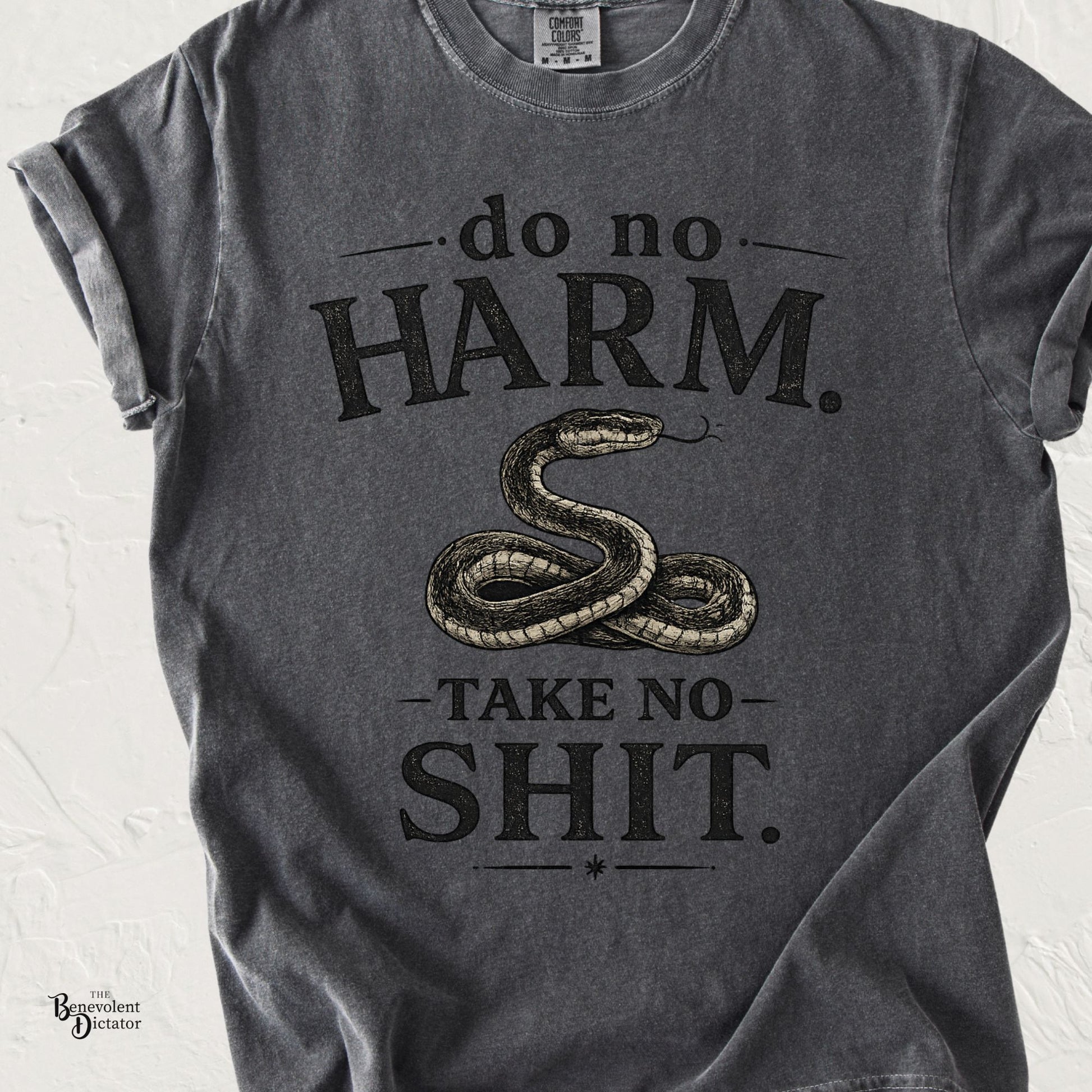 Black graphic t-shirt featuring vintage typography reading Do No Harm. Take No Shit. with an illustrated coiled snake in the center.