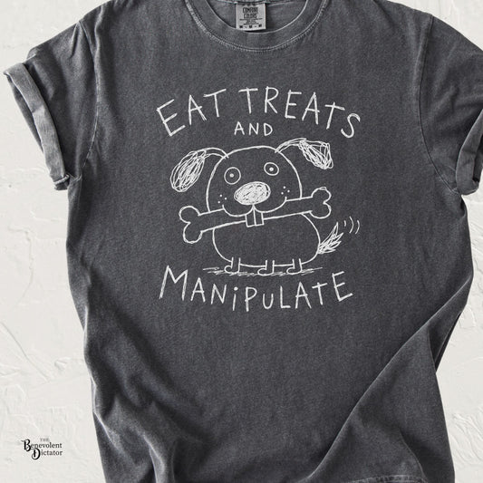 Pepper gray graphic t-shirt featuring a childlike doodle dog holding a bone with the phrase “Eat Treats and Manipulate” in hand-drawn lettering.