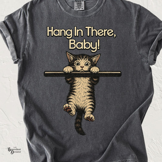 Comfort Colors pepper t-shirt featuring a vintage-style kitten hanging from a bar with the phrase "Hang In There, Baby!" inspired by the classic 1970s motivational poster.