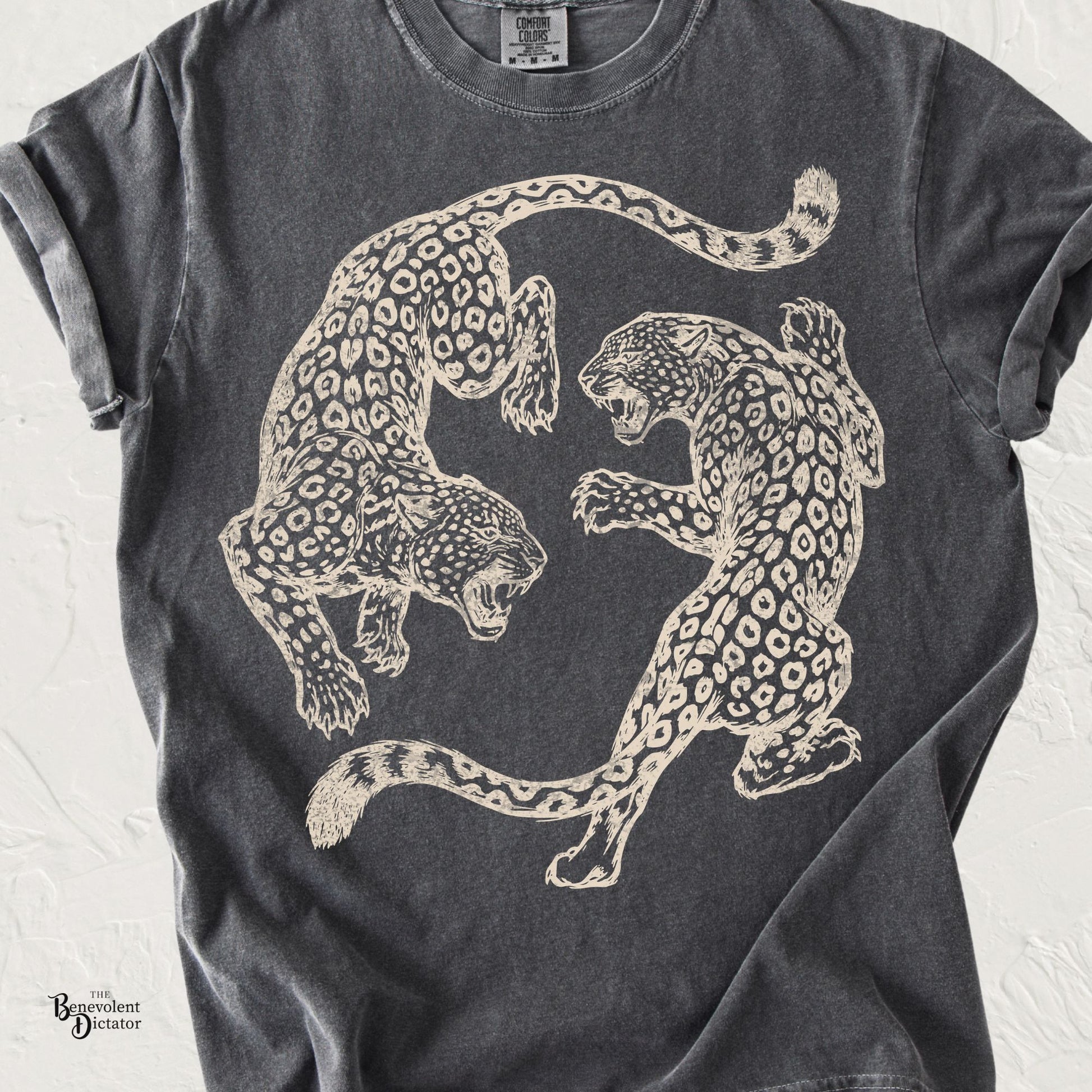 Vintage-inspired graphic featuring two mirrored leopards in a circular composition printed in distressed cream on a Comfort Colors shirt.