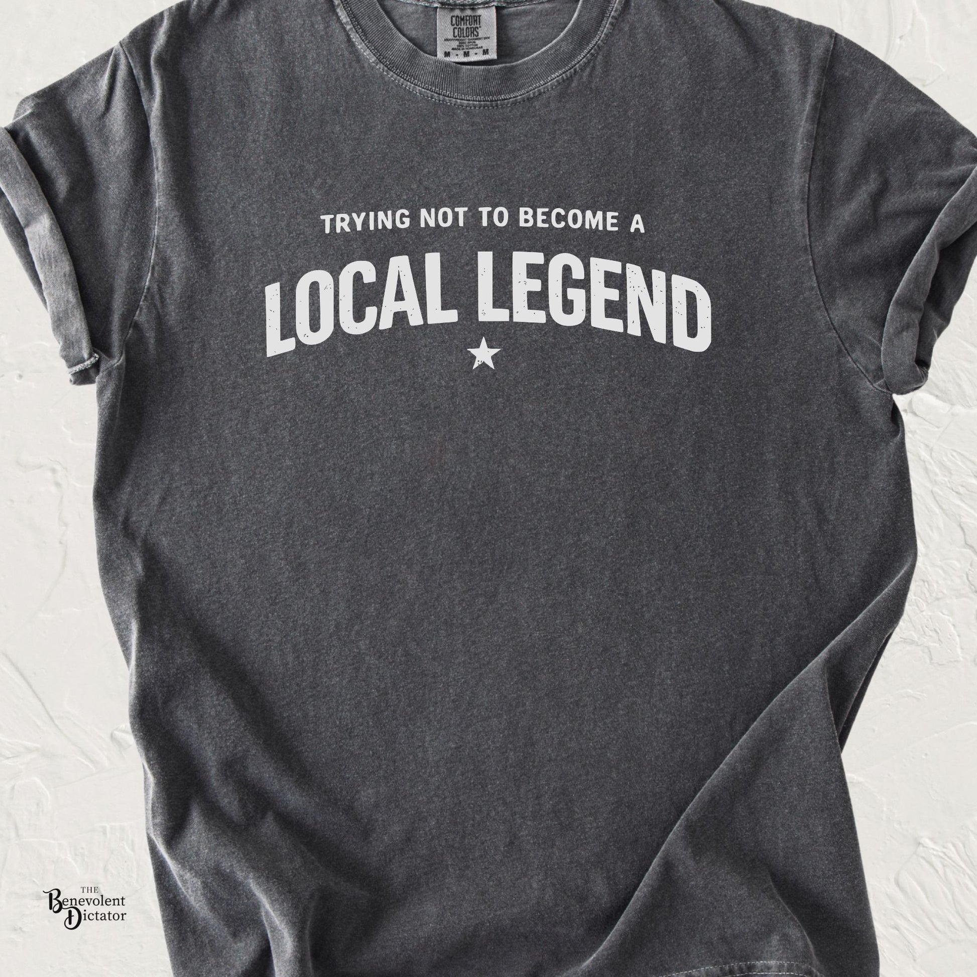 Typography t-shirt featuring the phrase Trying Not to Become a Local Legend in bold vintage lettering.