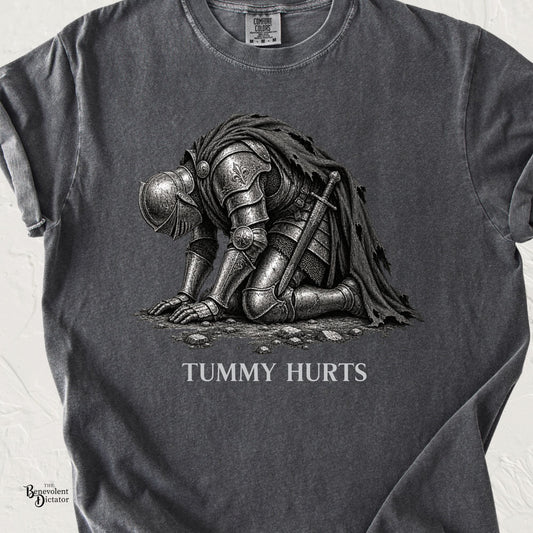 Pepper Comfort Colors t-shirt featuring a heavily armored medieval knight collapsed on his knees with the words “Tummy Hurts.”