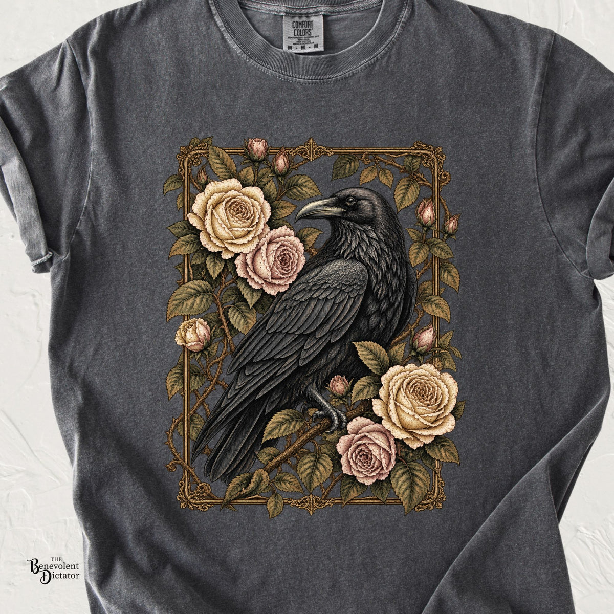 Pepper Comfort Colors t-shirt featuring a detailed black raven surrounded by antique pink and ivory garden roses, leafy vines and an ornate vintage botanical frame.