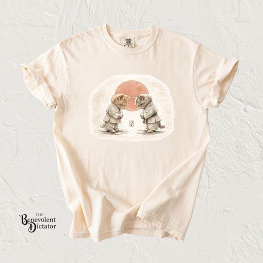 Beige t-shirt with a graphic of two elephants and a red sun on a textured white background.