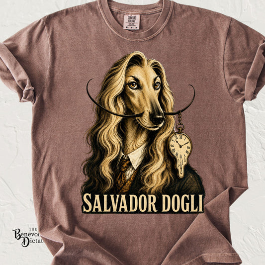 Elegant Afghan Hound illustrated as Salvador Dalí with a dramatic curled mustache, flowing hair, melting pocket watch, and the text "Salvador Dogli" on a Comfort Colors® t-shirt.