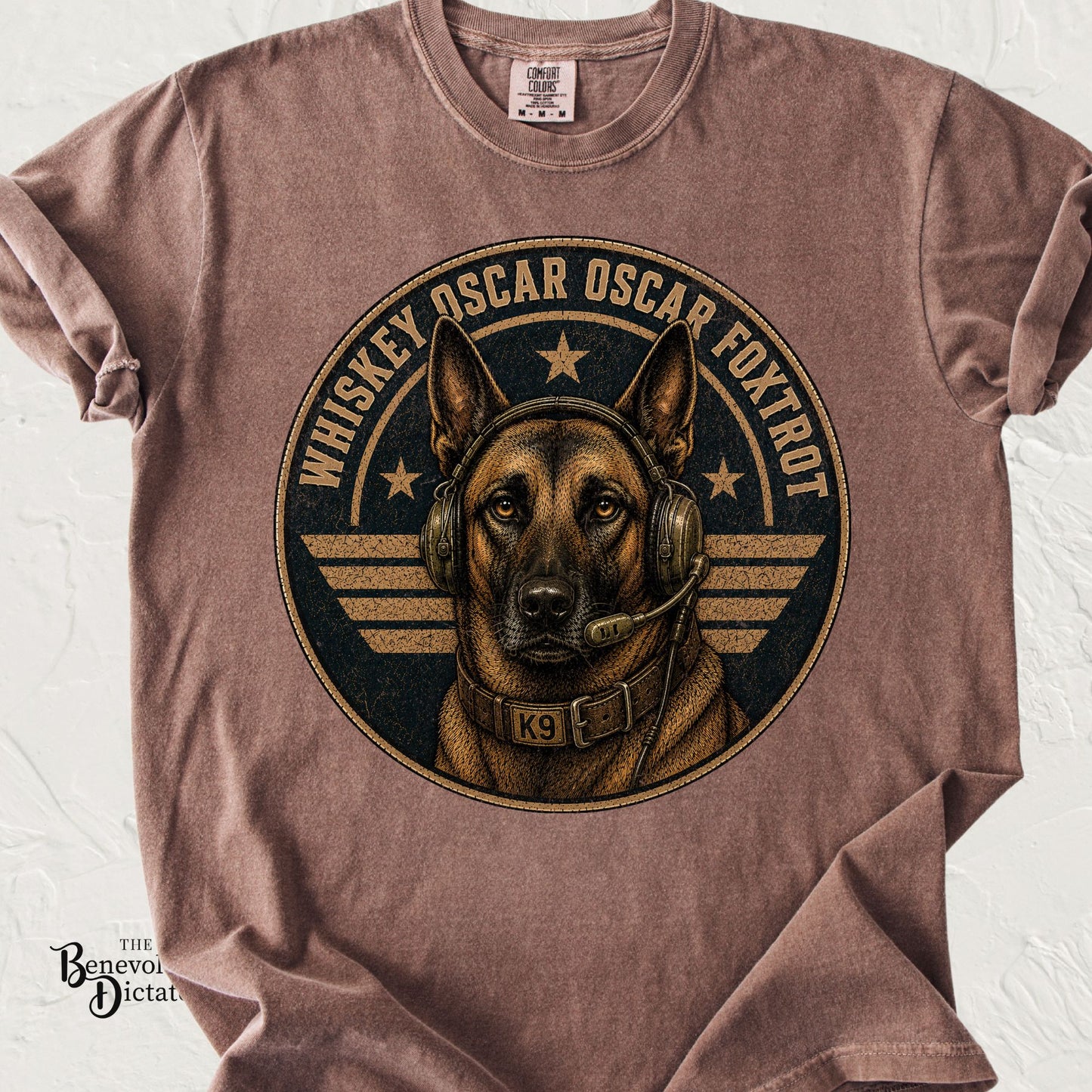 Brown Comfort Colors t-shirt featuring a Belgian Malinois military K9 wearing a communications headset and K9 collar with the phrase "Whiskey Oscar Oscar Foxtrot" in distressed vintage lettering around a military-style emblem.