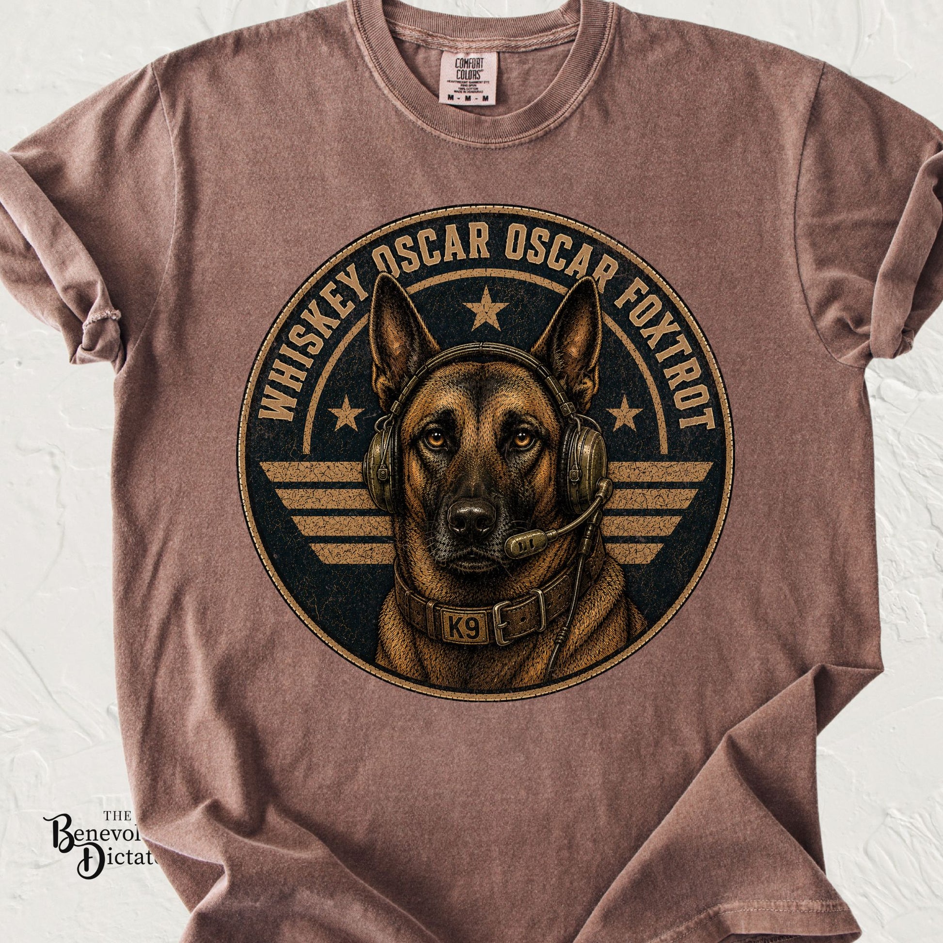 Brown Comfort Colors t-shirt featuring a Belgian Malinois military K9 wearing a communications headset and K9 collar with the phrase "Whiskey Oscar Oscar Foxtrot" in distressed vintage lettering around a military-style emblem.