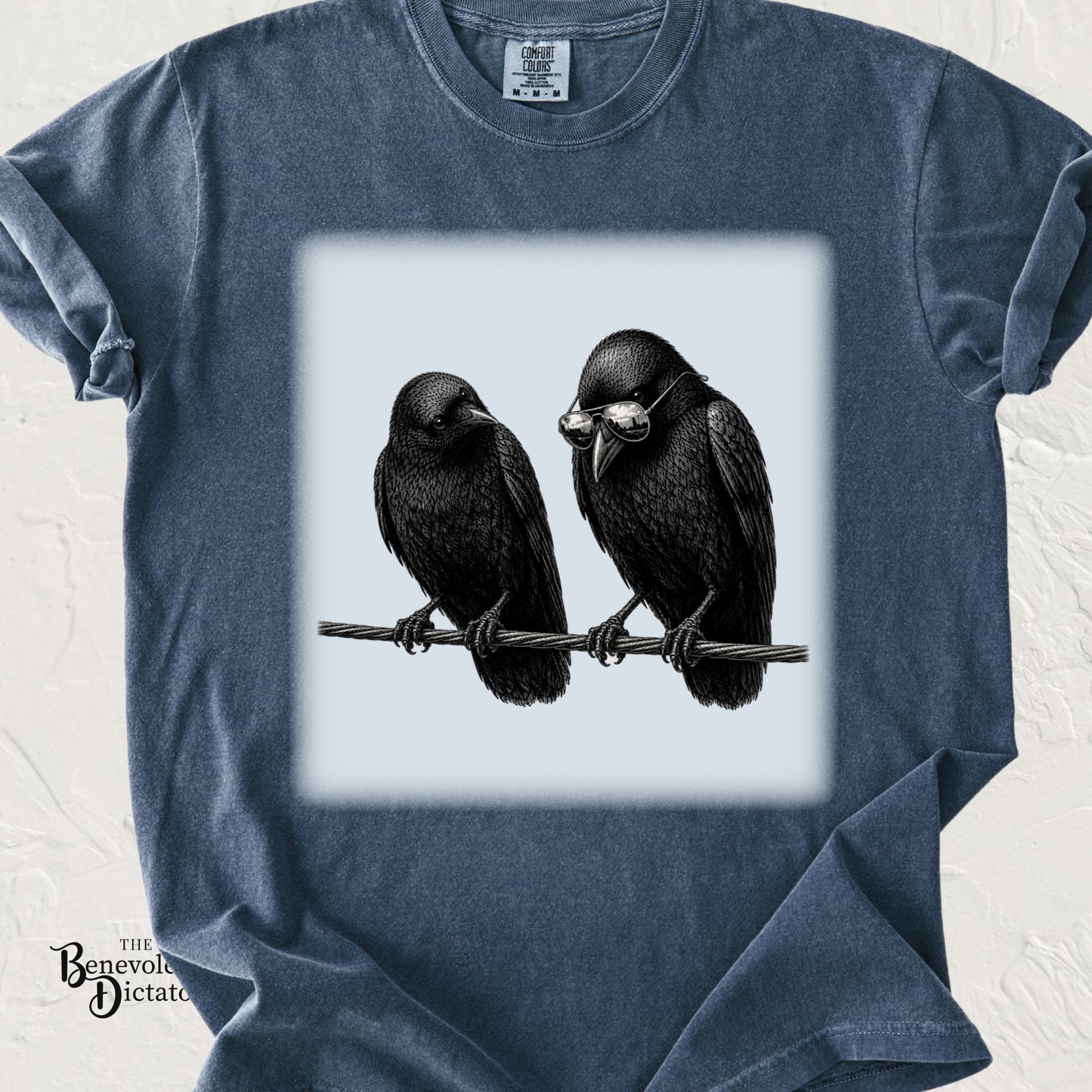 Comfort Colors Blue Jean t-shirt featuring two vintage-style crows perched on a wire, one wearing reflective aviator sunglasses, inspired by crows' fascination with collecting shiny objects.